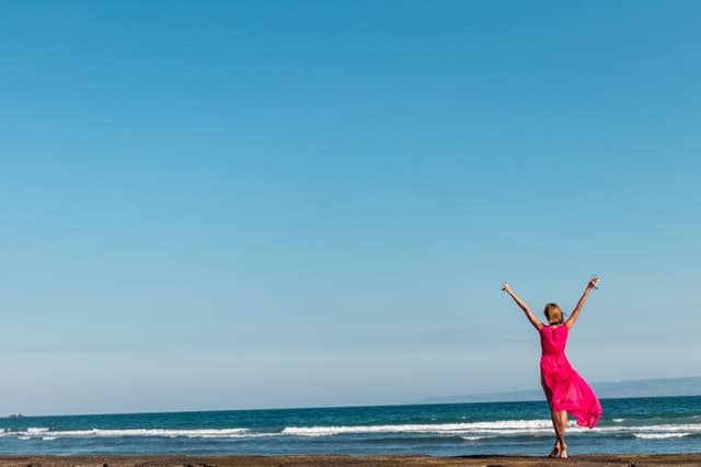 kobieta w czerwonej sukience stojąca na wybrzeżu