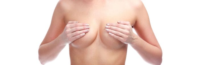 kobieta zakrywa dłońmi piersi