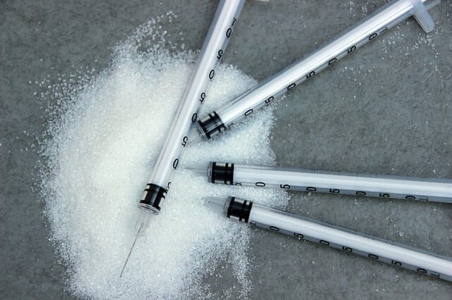 wysypany cukier i strzykawki z insuliną