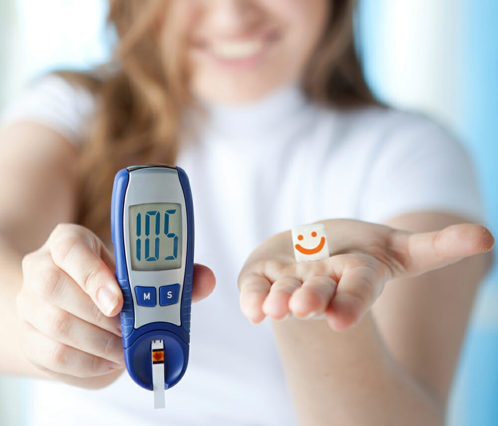 kobieta pokazuje glukometr, na którym widnieje prawidłowy wynik