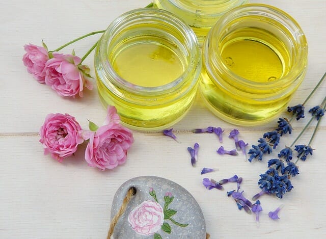 olejki kosmetyczne w słoiczkach, obok świeże kwiaty