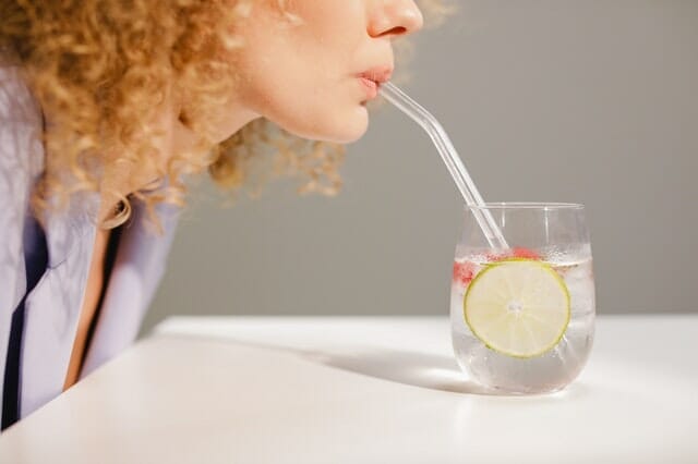kobieta pije wodę przez słomkę