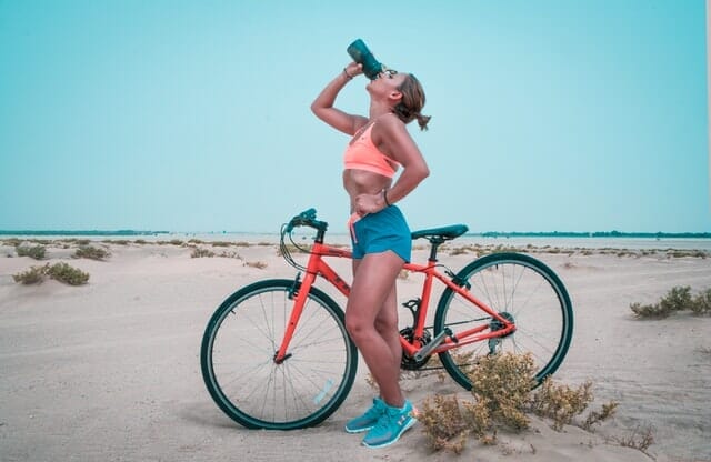 kobieta pije wodę z bidonu po jeździe rowerem