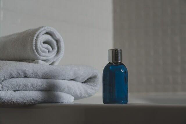niebieska butelka z szamponem, obok ręczniki