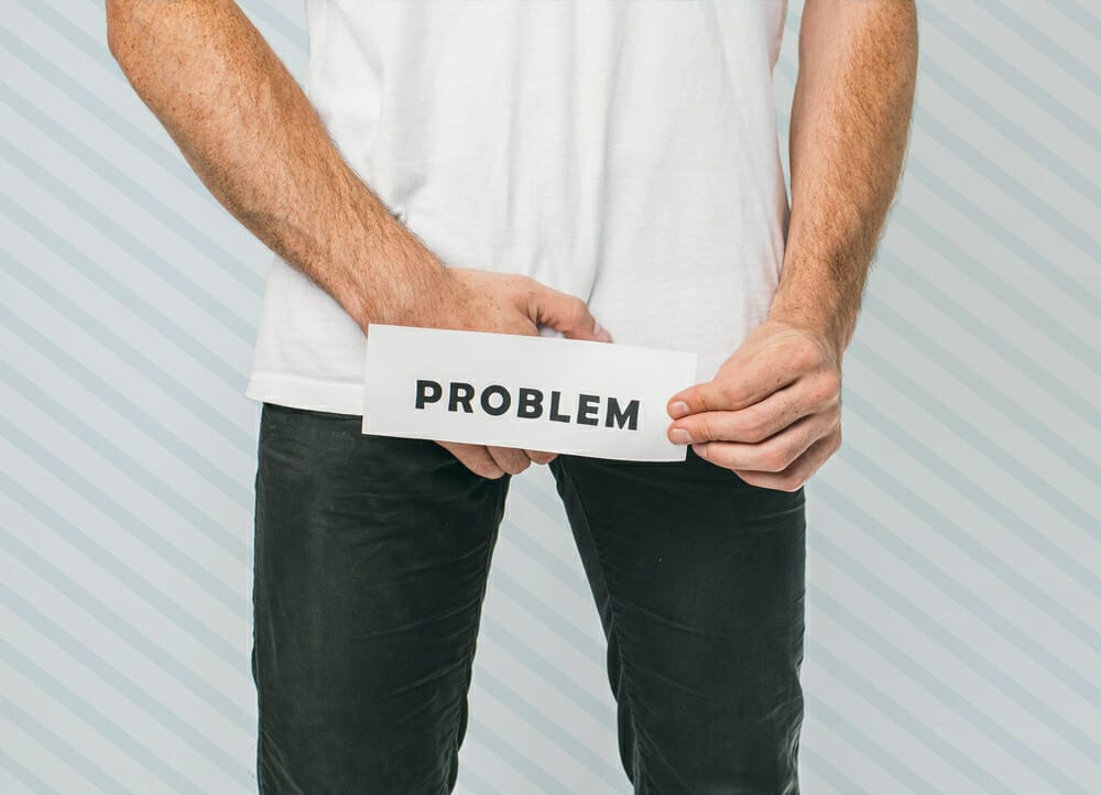 mężczyzna trzyma kartkę z napisem "problem" w okolicy krocza