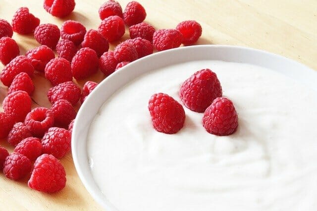 jogurt w miseczce, obok maliny