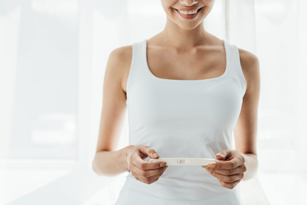 zadowolona kobieta trzyma test ciążowy z pozytywnym wynikiem